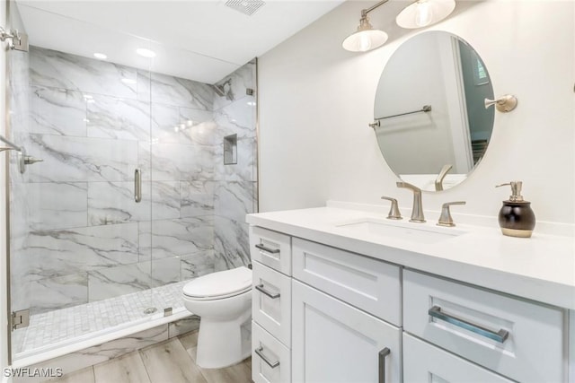 bathroom featuring toilet, vanity, and a shower with shower door