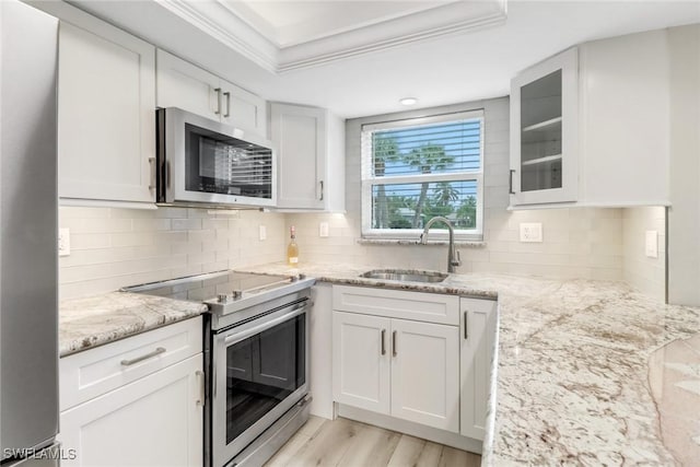 kitchen featuring white cabinetry, appliances with stainless steel finishes, backsplash, a tray ceiling, and sink