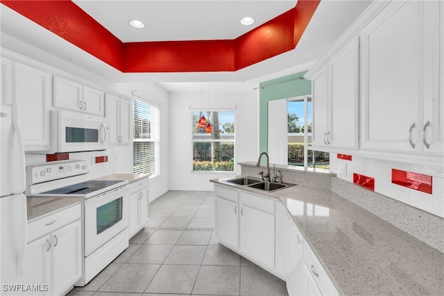 kitchen with white appliances, white cabinets, a raised ceiling, and light stone countertops