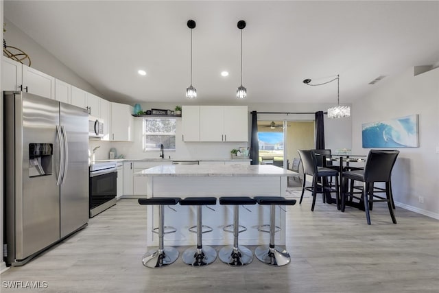 kitchen with appliances with stainless steel finishes, pendant lighting, white cabinets, and a kitchen island