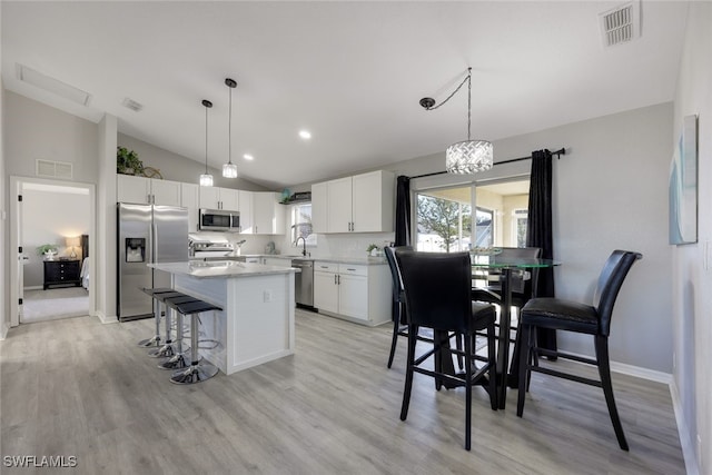 kitchen featuring a center island, stainless steel appliances, decorative backsplash, lofted ceiling, and white cabinetry