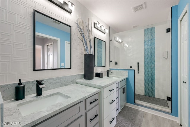 bathroom with a shower with shower door and vanity