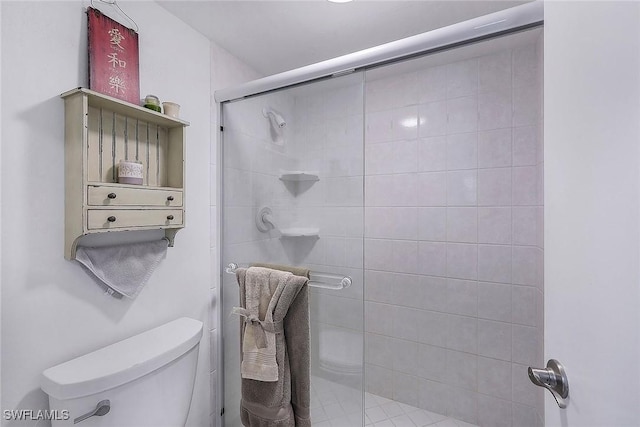 bathroom featuring toilet and a shower with shower door