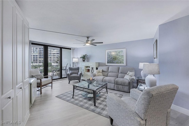 living room featuring floor to ceiling windows, ceiling fan, and light wood-type flooring