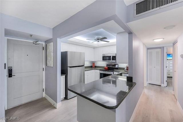 kitchen with stainless steel appliances, white cabinetry, ceiling fan, light hardwood / wood-style floors, and kitchen peninsula