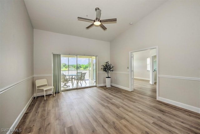 unfurnished room with light wood-type flooring, ceiling fan, and high vaulted ceiling