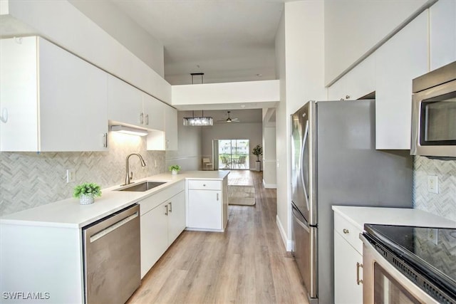 kitchen featuring ceiling fan, kitchen peninsula, sink, stainless steel appliances, and white cabinets