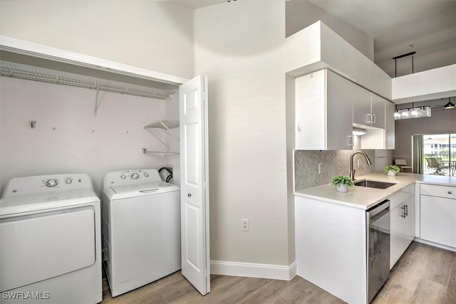 clothes washing area featuring independent washer and dryer, sink, and light hardwood / wood-style flooring