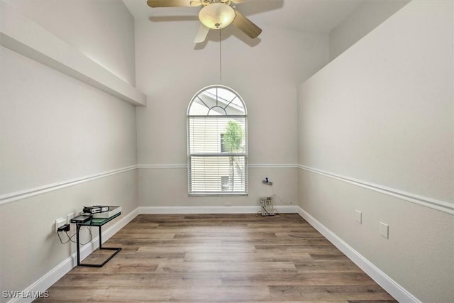 empty room featuring ceiling fan, hardwood / wood-style flooring, and high vaulted ceiling