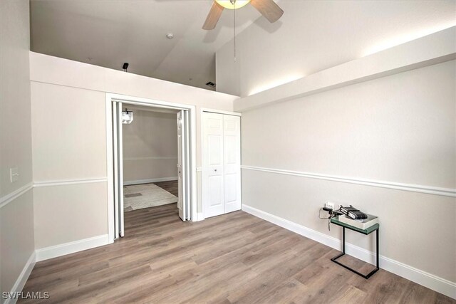 empty room with high vaulted ceiling, wood-type flooring, and ceiling fan