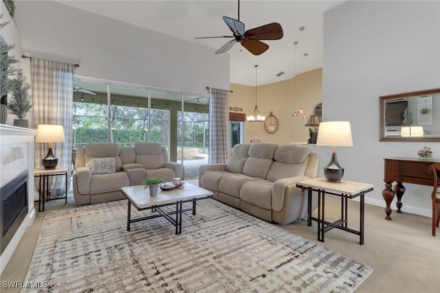 living room featuring a high ceiling, light colored carpet, and ceiling fan with notable chandelier