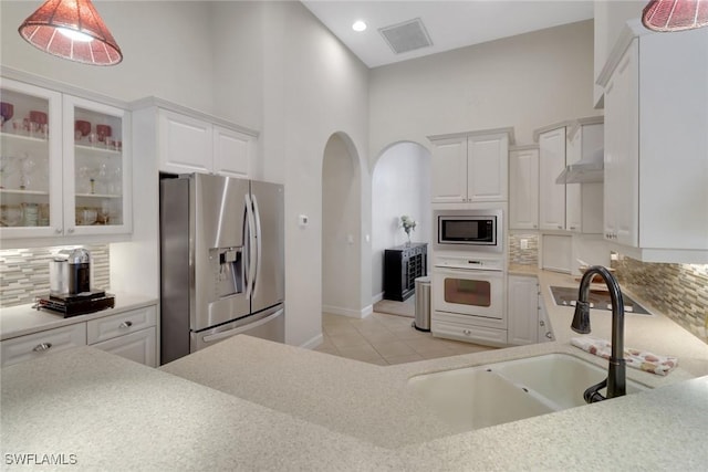 kitchen with decorative backsplash, sink, hanging light fixtures, appliances with stainless steel finishes, and white cabinets