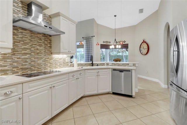 kitchen featuring sink, hanging light fixtures, stainless steel appliances, white cabinets, and wall chimney exhaust hood