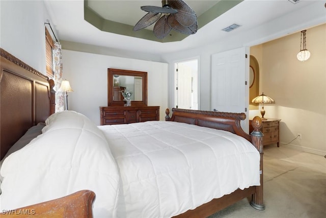 carpeted bedroom with ceiling fan and a raised ceiling