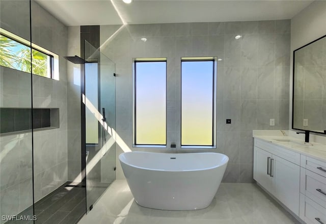 bathroom featuring tile walls, plus walk in shower, and vanity