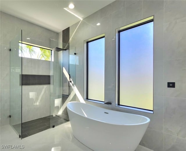 bathroom with tile walls and shower with separate bathtub