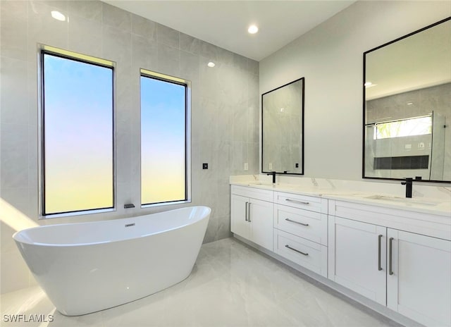 bathroom featuring tile walls, a washtub, and vanity