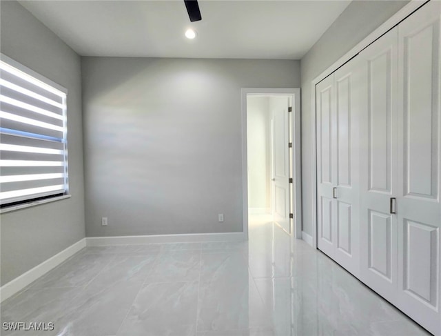 unfurnished bedroom with ceiling fan and a closet