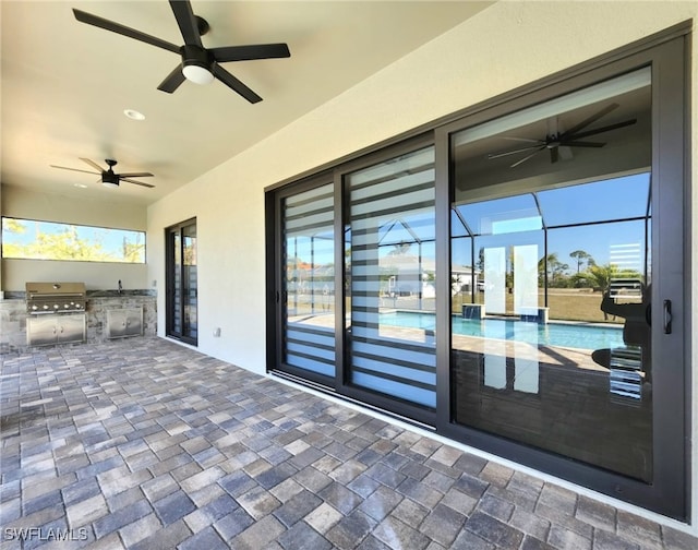 view of patio featuring area for grilling, ceiling fan, and glass enclosure