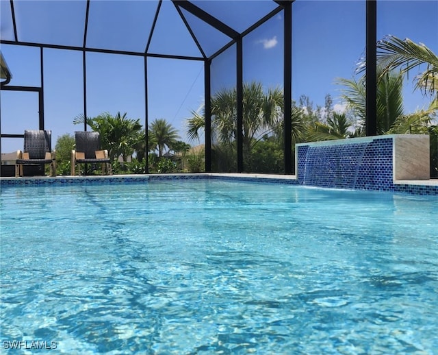 view of swimming pool featuring pool water feature and glass enclosure