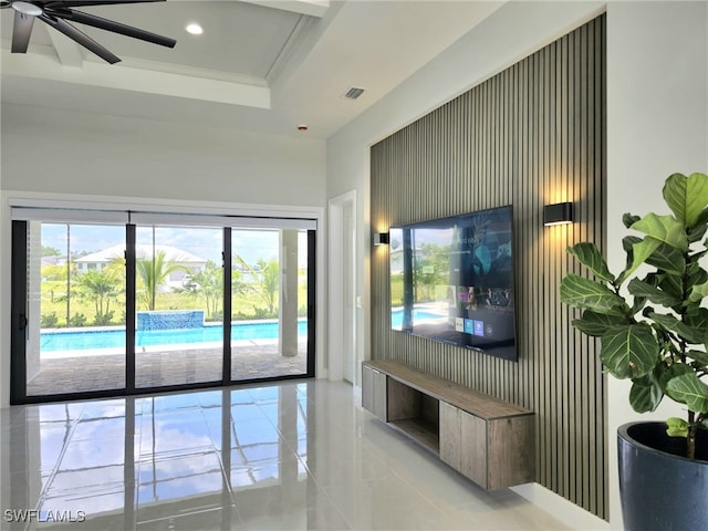 living room with a raised ceiling, ceiling fan, crown molding, and light tile patterned floors