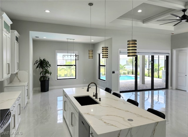 kitchen with white cabinets, ceiling fan, an island with sink, and sink