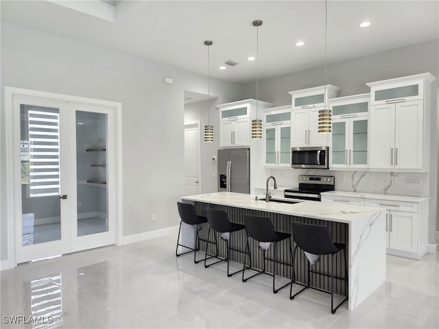 kitchen with stainless steel appliances, an island with sink, hanging light fixtures, a kitchen bar, and backsplash