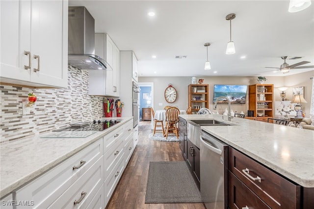 kitchen with white cabinetry, appliances with stainless steel finishes, dark hardwood / wood-style floors, hanging light fixtures, and wall chimney exhaust hood