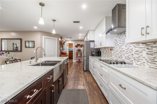 kitchen featuring white cabinetry, appliances with stainless steel finishes, pendant lighting, light stone countertops, and wall chimney exhaust hood