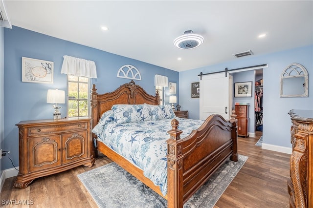 bedroom featuring a barn door, a closet, dark wood-type flooring, and a walk in closet