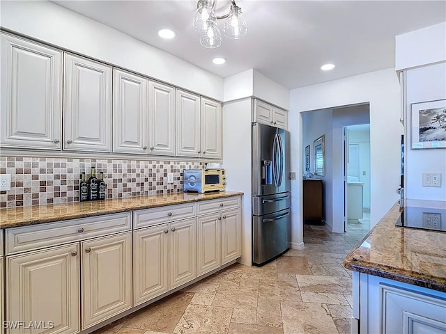 kitchen with white cabinetry, dark stone counters, stainless steel fridge with ice dispenser, and decorative backsplash