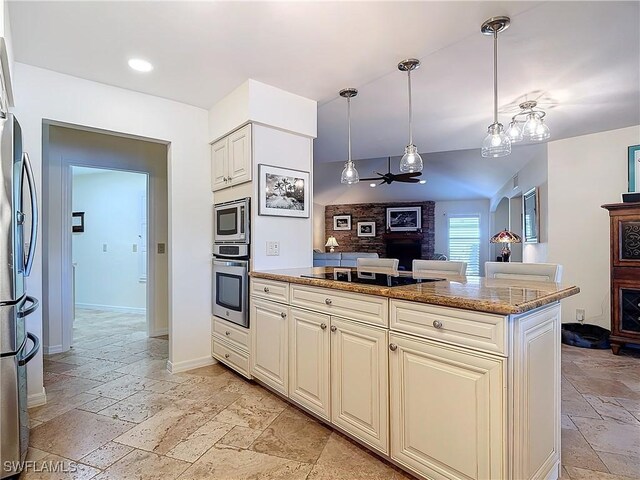 kitchen with stainless steel appliances, pendant lighting, stone counters, and cream cabinetry