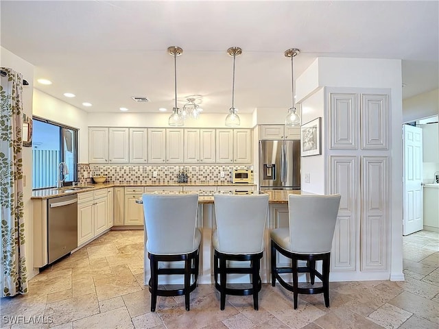 kitchen with appliances with stainless steel finishes, a breakfast bar, decorative light fixtures, sink, and decorative backsplash