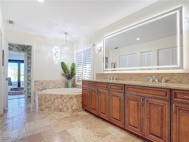 bathroom featuring an inviting chandelier, vanity, tiled bath, and a wealth of natural light