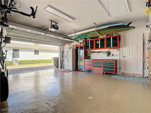 garage featuring a garage door opener and white refrigerator with ice dispenser