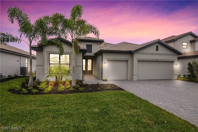 view of front facade featuring a garage, decorative driveway, central AC, and a front lawn