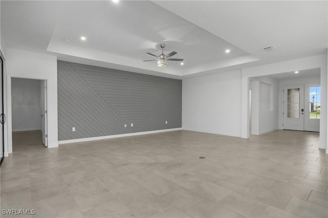 interior space with recessed lighting, a raised ceiling, visible vents, a ceiling fan, and baseboards