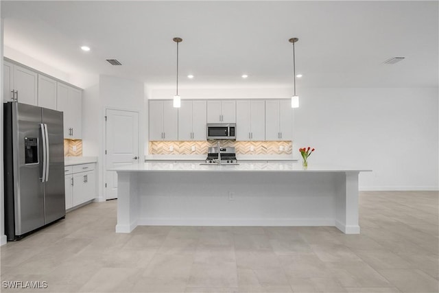 kitchen with a kitchen island with sink, stainless steel appliances, light countertops, pendant lighting, and backsplash