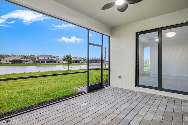 unfurnished sunroom with a residential view, a water view, and ceiling fan