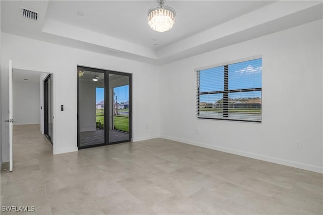 unfurnished room featuring a raised ceiling, visible vents, and baseboards