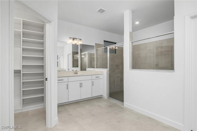 bathroom featuring a spacious closet, vanity, a shower stall, and visible vents