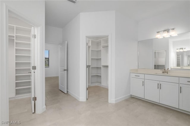 full bathroom featuring a walk in closet, visible vents, vanity, and baseboards