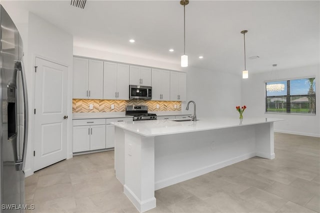 kitchen with stainless steel appliances, light countertops, hanging light fixtures, a kitchen island with sink, and white cabinetry