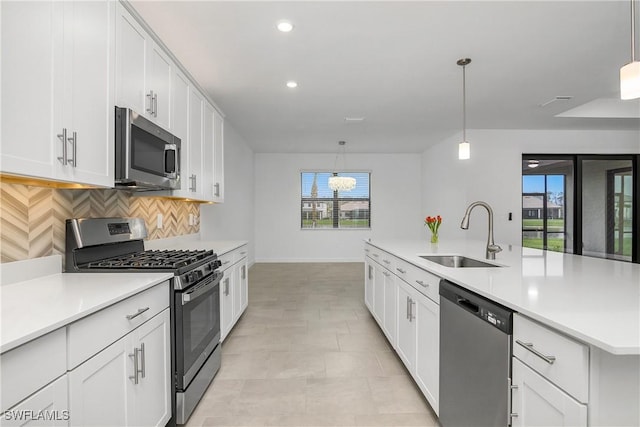 kitchen featuring light countertops, stainless steel appliances, a sink, and decorative light fixtures