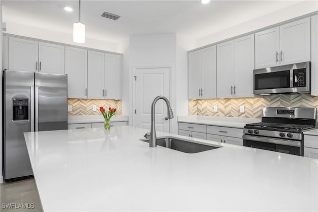 kitchen featuring pendant lighting, stainless steel appliances, a sink, and light countertops