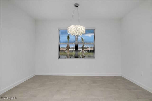 unfurnished room featuring a notable chandelier and baseboards