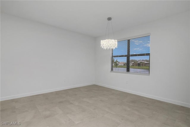 unfurnished room with an inviting chandelier and baseboards