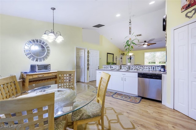 dining room featuring ceiling fan with notable chandelier, vaulted ceiling, light hardwood / wood-style flooring, and sink