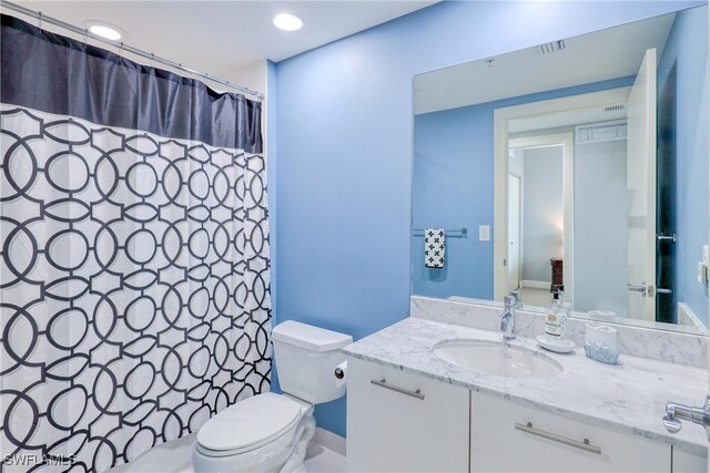 bathroom featuring toilet, vanity, and a shower with curtain