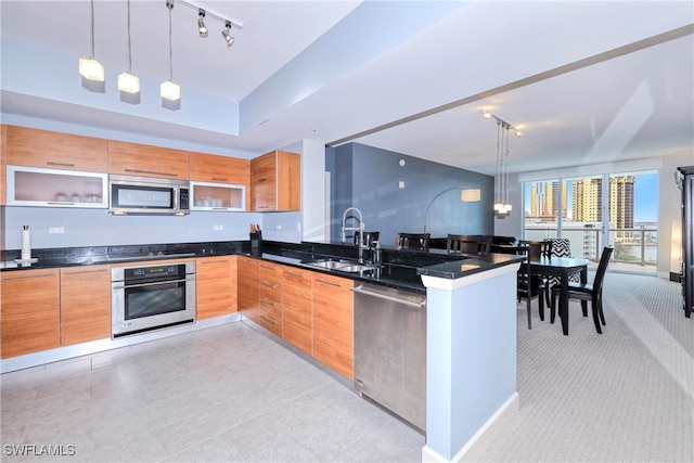 kitchen featuring kitchen peninsula, hanging light fixtures, track lighting, appliances with stainless steel finishes, and sink